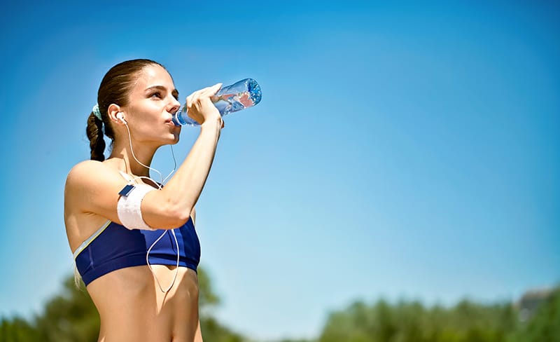 woman athlete takes a break, she drinking water, out on a run o